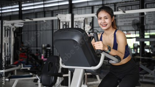 Smiling fit young woman cycling machines in sports club.