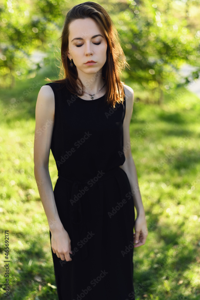 Portrait of young woman in black dress in the park. Portrait of young woman in black dress in the park.