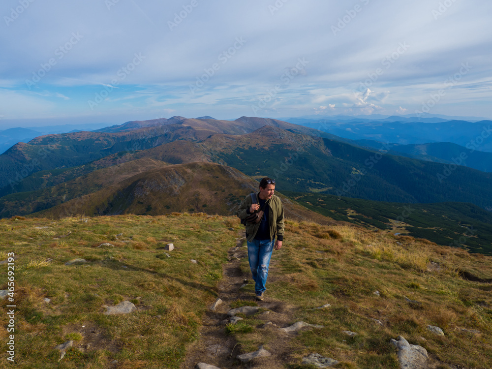 Man standing on top of the mountain relaxing and enjoying beautiful summer landscape. A panoramic view of the Carpathian Mountains from Hoverla in Ukraine. Hiking adventure lifestyle extreme vacations