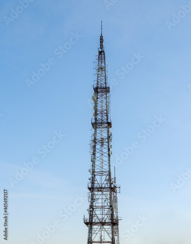 High telecommunications tower. Blue sky background. Wave communication antennas.