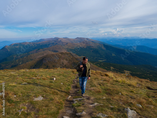 Man standing on top of the mountain relaxing and enjoying beautiful summer landscape. A panoramic view of the Carpathian Mountains from Hoverla in Ukraine. Hiking adventure lifestyle extreme vacations