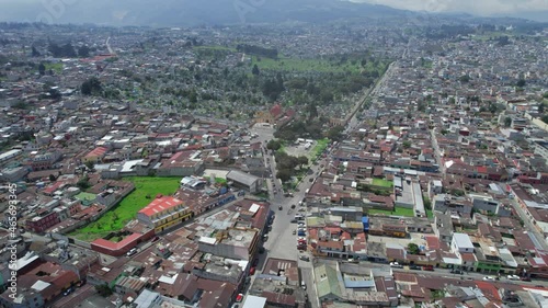 Drone aerial footage of urban colonial traffic driving through streets of Central American highlands city Quetzaltenango, Xela, Guatemala on a sunny day near Parque El Calvario and Cementerio General. photo