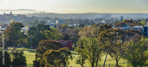Panorama of Melbourne suburbs, from Brunswick looking towards the east on a misty morning, with a local sports oval in the foreground