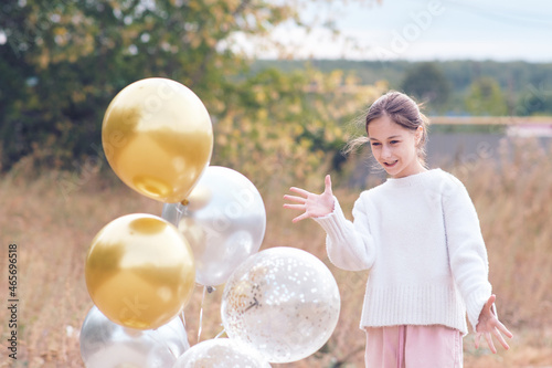 Happy teenage girl in white sweater mentally controls gel balloons.