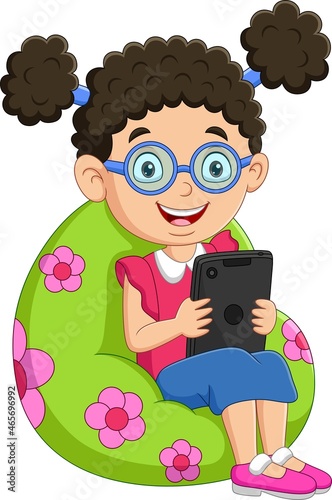 Little girl playing tablet on big pillow