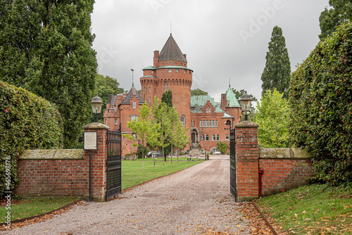 the gate to a romantick red castle inside a park on a green lawn photo