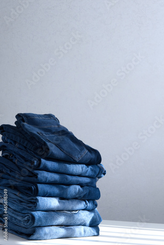 a pile of blue jeans on a light background. Close up. Copy space. Sunlight (ID: 465698349)