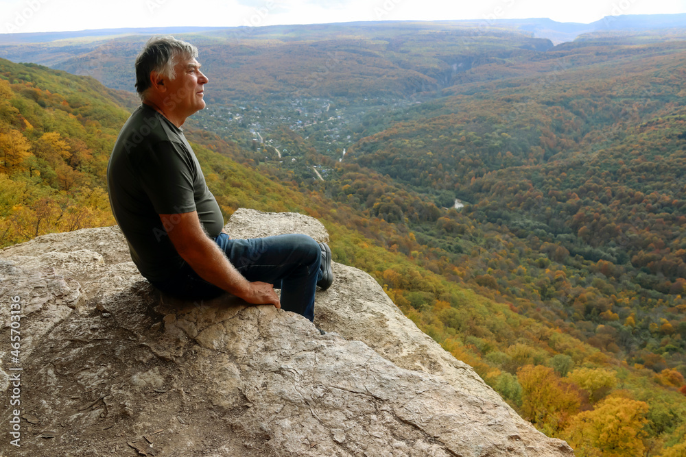 A man on the edge of a cliff looking into the distance.