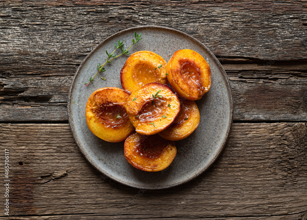 Baked peaches with honey and cinnamon in a ceramic plate, top view Baked peaches with honey and cinnamon in a ceramic plate, top view