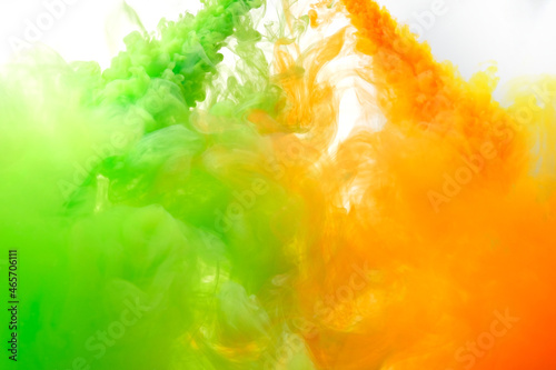 Ink in the water. A splash of green and orange paint. Abstract background. selective focus.