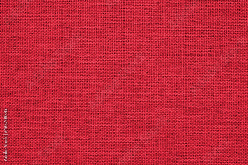 Close-up of a dark red woven surface. The texture is similar to linen. Fabric background for Christmas or New Year. Textured woven backdrop