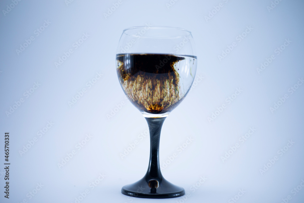 Dark brown food coloring diffuse in water inside wine glass with  for slogan or advertising text message, over isolated grey background.