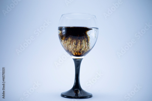 Dark brown food coloring diffuse in water inside wine glass with for slogan or advertising text message, over isolated grey background.