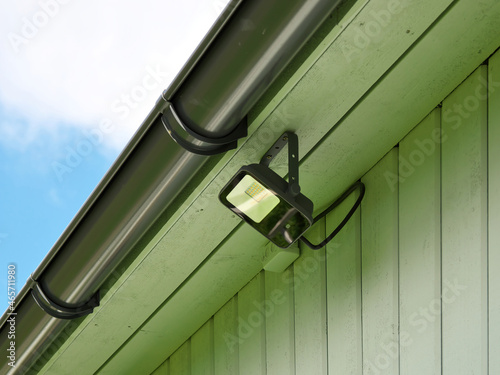 Installed LED floodlight under the roof of a wooden house.