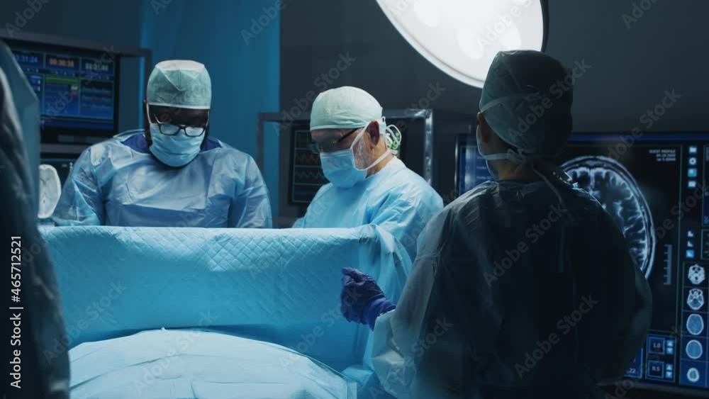 Multiracial team of professional medical surgeons performs the surgical operation in a modern hospital. Doctors are working to save the patient. Medicine, health and neurosurgery. Multiracial team of professional medical surgeons performs the surgical operation in a modern hospital. Doctors are working to save the patient. Medicine, health and neurosurgery.