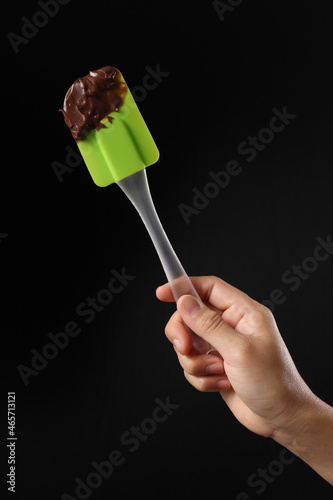 Chef holding spatula and melted chocolate on black background