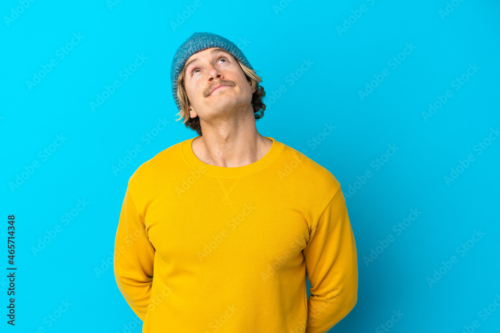 Handsome blonde man isolated on blue background and looking up Handsome blonde man isolated on blue background and looking up