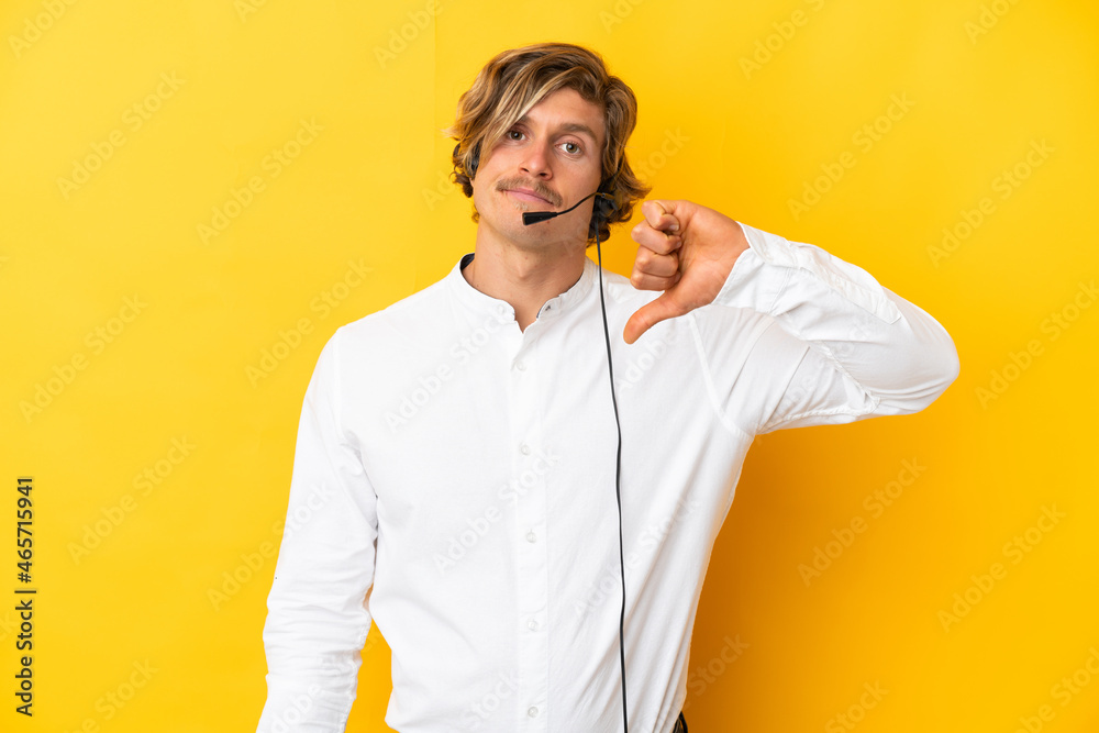 Telemarketer man working with a headset isolated on yellow background showing thumb down with negative expression Telemarketer man working with a headset isolated on yellow background showing thumb down with negative expression