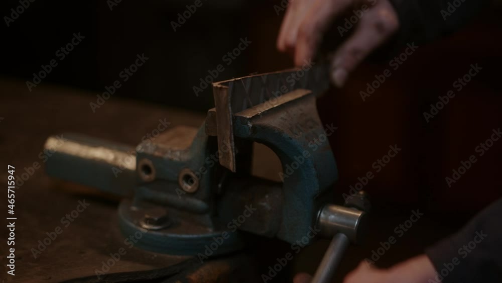 Close-up at part of a rustic old metal grip clamp, young blacksmith clamps the metal or iron part into the clamp Close-up at part of a rustic old metal grip clamp, young blacksmith clamps the metal or iron part into the clamp