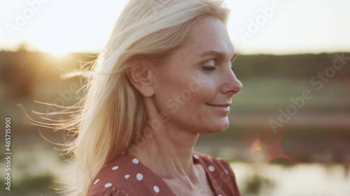 Close-up view of handsome woman walking on the field at sunset
