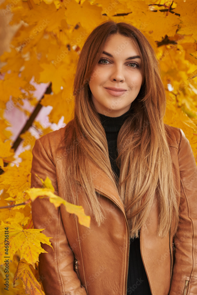 young beautiful woman stands next to beautiful autumn yellow foliage