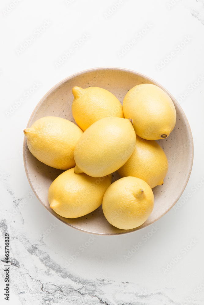 Several yellow bright lemons in a plate on a light background. Bright citruses.