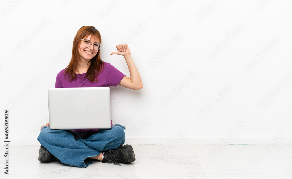 redhead girl with a laptop sitting on the floor proud and self-satisfied