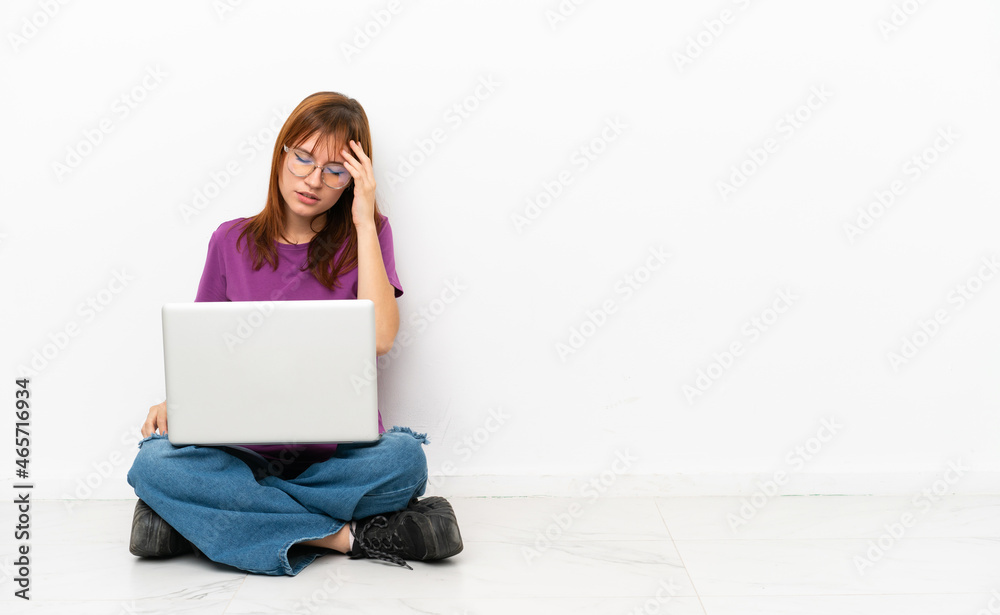 redhead girl with a laptop sitting on the floor with headache redhead girl with a laptop sitting on the floor with headache
