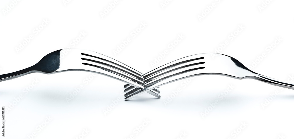 Two forks interwoven isolated on white background with subtle shadow Two forks interwoven isolated on white background with subtle shadow
