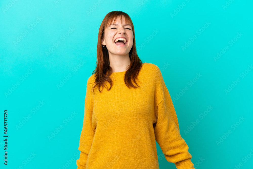 Redhead girl isolated on blue background laughing Redhead girl isolated on blue background laughing