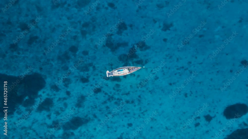 Yacht swaying and bobbing in the ocean revealing reef in the clear blue waters. High view looking down Yacht swaying and bobbing in the ocean revealing reef in the clear blue waters. High view looking down