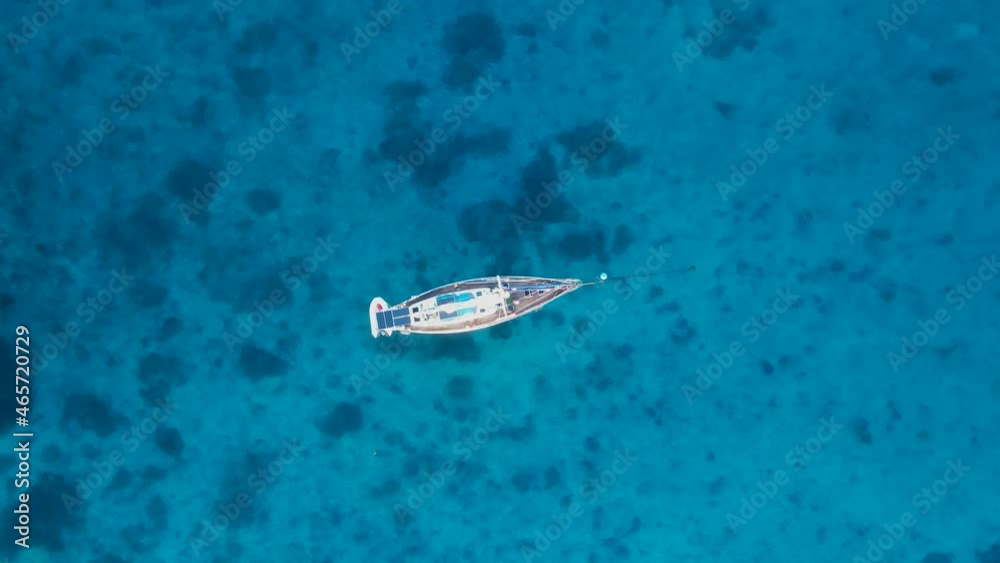 Yacht swaying and bobbing in the ocean revealing reef in the clear blue waters. High view looking down Yacht swaying and bobbing in the ocean revealing reef in the clear blue waters. High view looking down