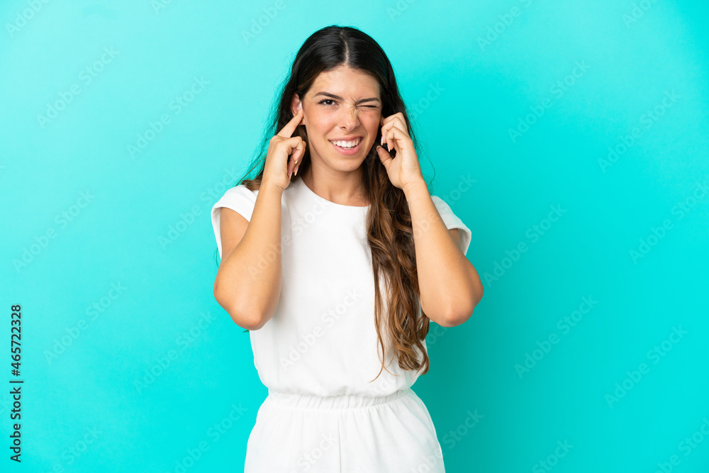 Fototapeta premium Young caucasian woman isolated on blue background frustrated and covering ears