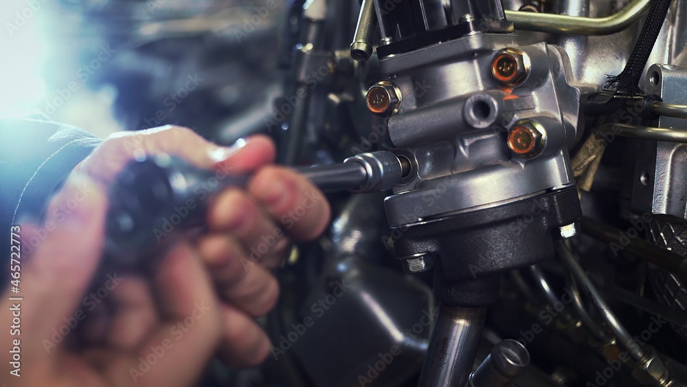 An auto mechanic works on a car engine in the mechanics ' garage. Repair services. Close-up An auto mechanic works on a car engine in the mechanics ' garage. Repair services. Close-up
