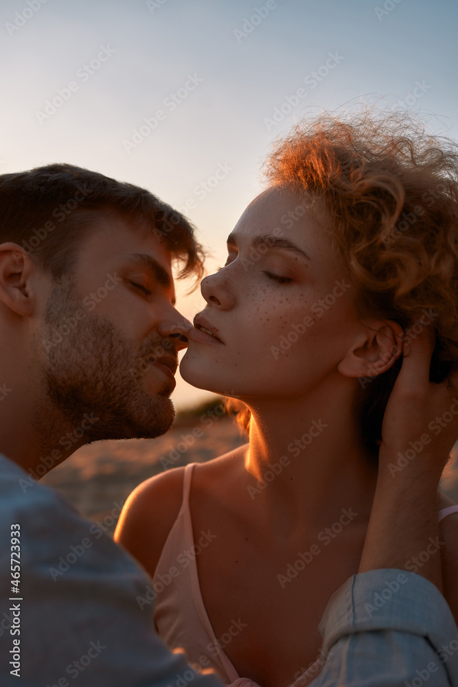Beautiful young people in love, couple looking passionate, kissing each other on the beach at sunset Beautiful young people in love, couple looking passionate, kissing each other on the beach at sunset