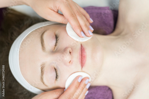 Young woman at reception of cosmetologist. Face cleansing. Girl in beauty salon. Top view.