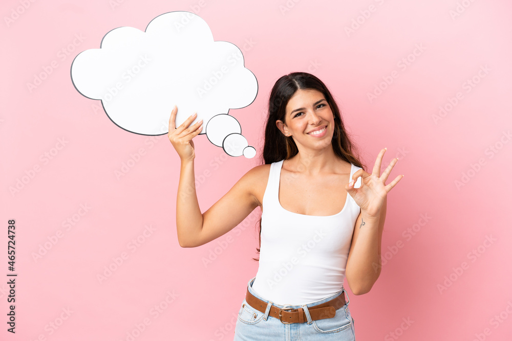 Young caucasian woman isolated on pink background holding a thinking speech bubble and doing OK sign Young caucasian woman isolated on pink background holding a thinking speech bubble and doing OK sign