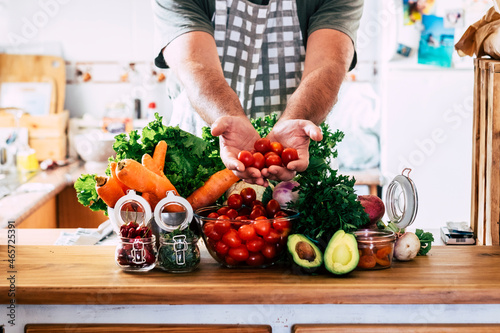 Man hands show fresh vegetables and fruits on a table in the kitchen at home. Close up of raw food healthy ingredients for salads. People prepare lunch for vegetarian friends photo