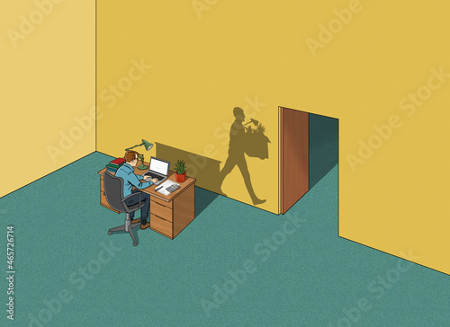 Man working in office while shadow has been made redundant photo