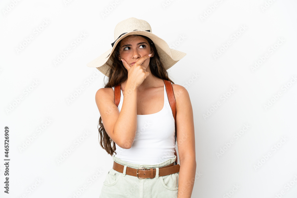 Young caucasian woman wearing a Pamela in summer holidays isolated on white background having doubts and with confuse face expression Young caucasian woman wearing a Pamela in summer holidays isolated on white background having doubts and with confuse face expression