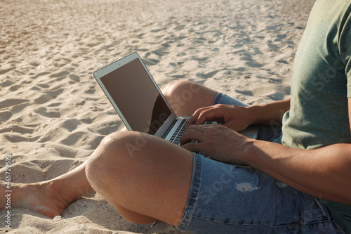 Man working with laptop on beach, closeup