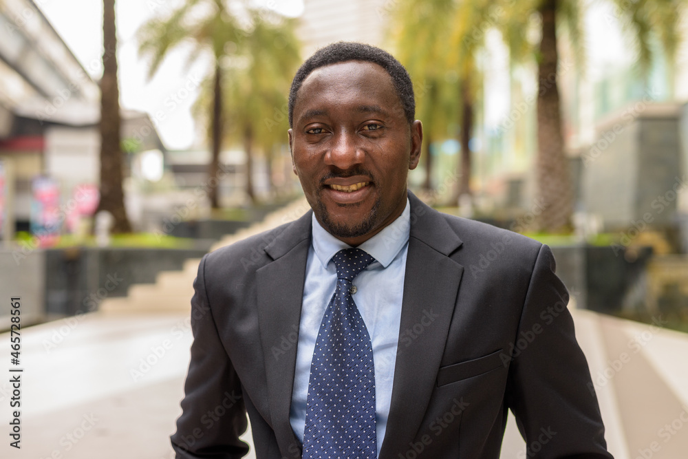Portrait of handsome African businessman in city smiling Portrait of handsome African businessman in city smiling