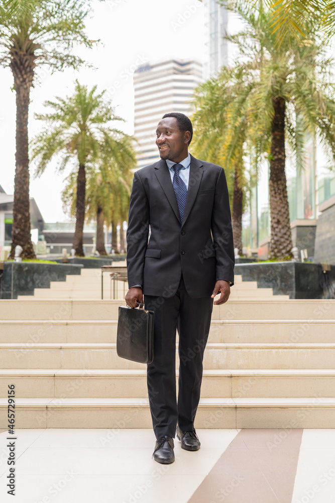 Full length portrait of handsome African businessman in city thinking Full length portrait of handsome African businessman in city thinking
