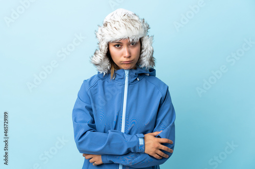 Young Uruguayan girl with winter hat isolated on blue background sad