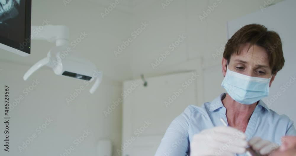 Caucasian female dental nurse with face mask examining teeth male patient at modern dental clinic Caucasian female dental nurse with face mask examining teeth male patient at modern dental clinic
