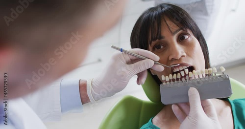 Caucasian male dentist examining teeth of female patient at modern dental clinic photo