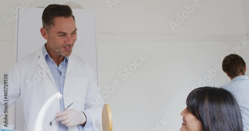 Smiling caucasian male dentist talking with female patient at modern dental clinic photo