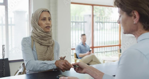 Biracial woman paying with credit card at reception at modern dental clinic photo