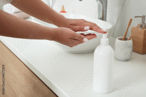 Beautiful young woman using washing gel in bathroom  closeup. Skin care cosmetic