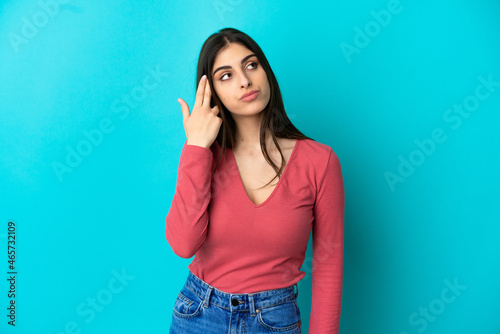 Young caucasian woman isolated on blue background with problems making suicide gesture